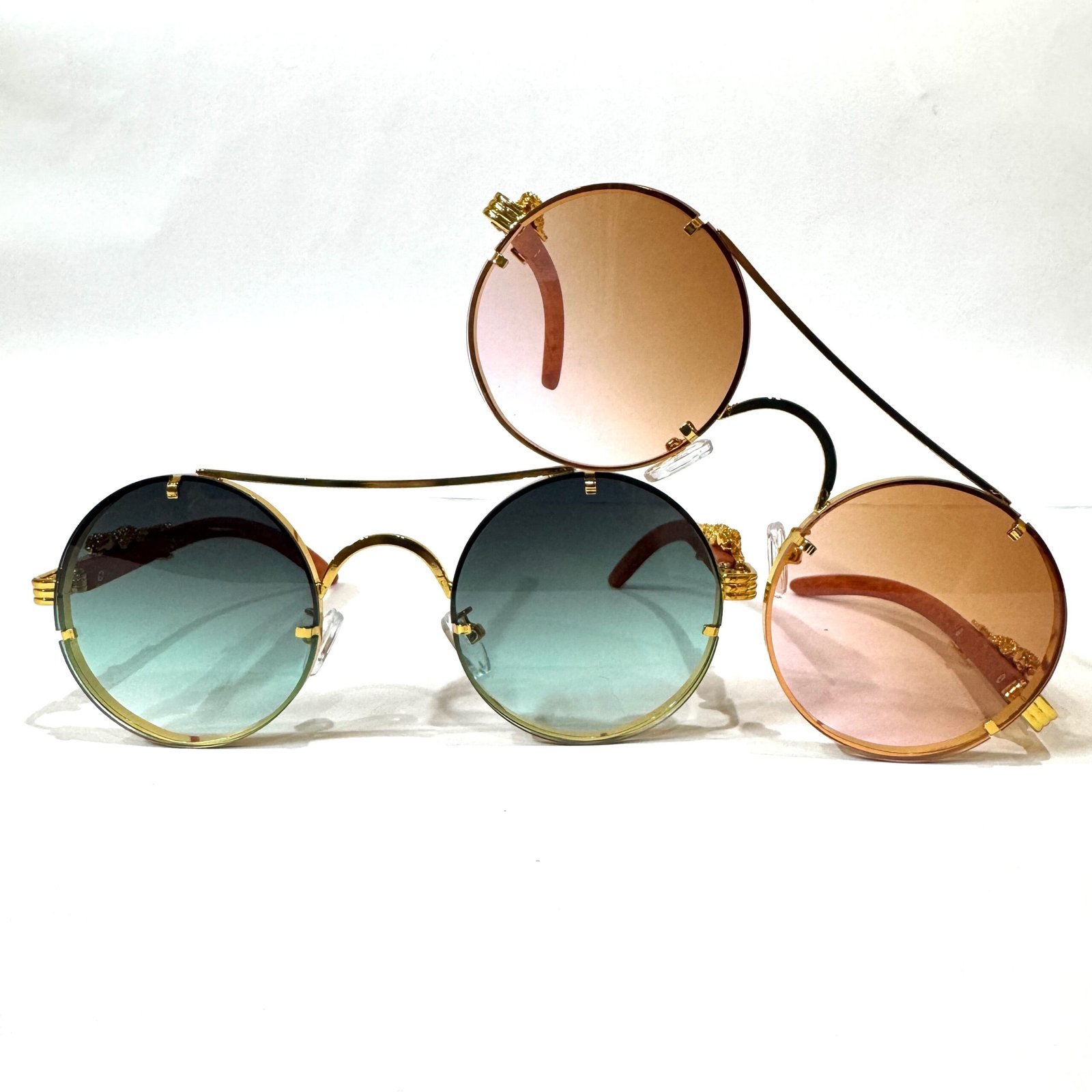 Three pairs of retro circular steampunk sunglasses with gold metal frames and gradient teal and rose-tinted lenses.